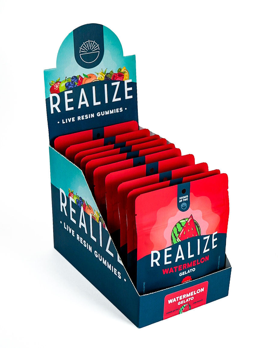 Wholesale display box featuring Realize Live Resin Gummies in Watermelon Gelato flavor. The display contains bright red 100mg Δ9 THC gummy pouches with a watermelon illustration and Realize branding, presented in a navy countertop display with a matching Watermelon Gelato product label.