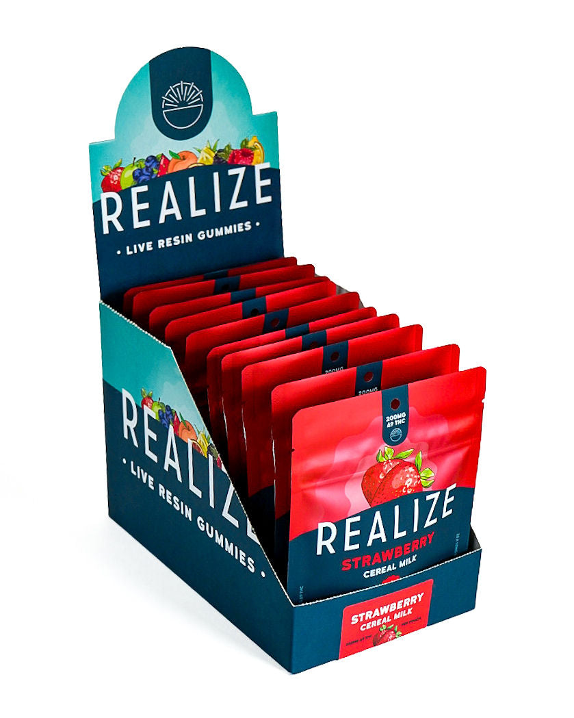 Wholesale display box featuring Realize Live Resin Gummies in Strawberry Cereal Milk flavor. The display contains bright red 200mg Δ9 THC gummy pouches with a strawberry illustration and Realize branding, presented in a navy countertop display with matching Strawberry Cereal Milk product label.